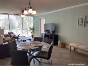 a living room with a tv and a table and chairs at Biloxi Beach-Good Vibes Condo in Biloxi