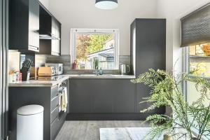 a kitchen with black cabinets and a window at Brand New 1-Bed Flat Steps from Clifton NTU Campus in Nottingham