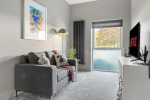 a living room with a gray couch and a window at Brand New 1-Bed Flat Steps from Clifton NTU Campus in Nottingham