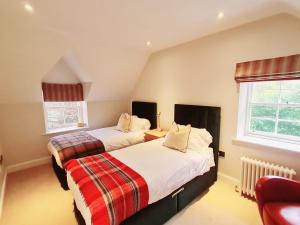 two beds in a room with two windows at The Head Gardeners Cottage, Dunbar in Dunbar