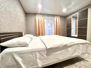 um quarto com uma grande cama branca e uma janela em ApartPoltava 2 ОКРЕМІ кімнати, новобудова, ДВА великих ліжка ЦЕНТР, КОРПУСНИЙ САД em Poltava