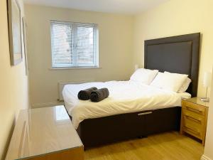 a bedroom with a bed with two bags on it at Travaal.©om - 2 Bed Serviced Apartment Farnborough in Farnborough