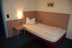 a small bedroom with a bed and a night stand at Hotel St. Paulushof 