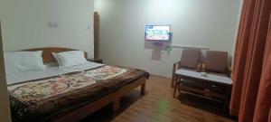 a bedroom with a bed and a tv and a chair at OYO Flagship 89130 Kohsheen Guest House 
