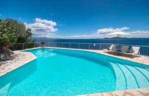 a swimming pool with two chairs and an umbrella at The Saints - Terrace House in Nisaki