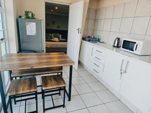 a kitchen with a table and two chairs and a microwave at Sea Breeze Manor - Green Unit in East London