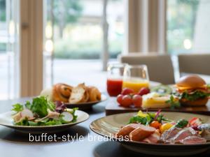 una tavola con piatti di cibo e un bicchiere di succo d'arancia di Hotel The Celestine Tokyo Shiba a Tokyo