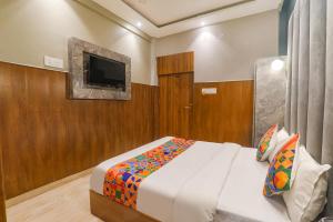 a bedroom with a bed and a flat screen tv at FabHotel Royal Palm Inn in Faizābād