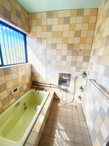 a bathroom with a green tub and a shower at シークレットベースゆふいん in Yufu