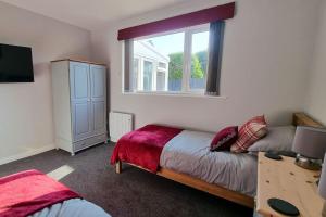 a bedroom with a bed and a desk and a window at Cornish Village Getaway in Gwennap