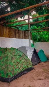 two tents and a green umbrella on the ground at Chalés Vila Irerê Itaúnas in Itaúnas