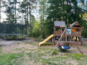 un parque infantil con una casa y un tobogán en Välkommen till vårt vackra hus, en Gnesta