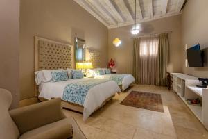 a bedroom with two beds and a couch and a television at Hotel Casa del Gobernador in Cartagena de Indias