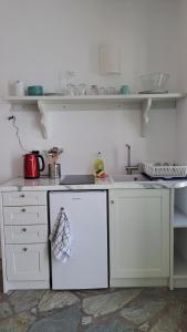 uma cozinha com armários brancos e um lavatório em Spice Suites-Lime em Amorgós