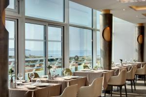 ein Restaurant mit Tischen und Stühlen und großen Fenstern in der Unterkunft Miramar La Cigale Hotel Thalasso & Spa in Arzon