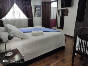 een slaapkamer met een groot wit bed met blauwe lakens bij Hotel el Che No apto para corruptos in Azogues