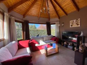 Una sala de estar con un sofá y un televisor. en La casa de la colina, en San Carlos de Bariloche