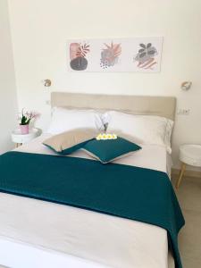 - un lit avec des draps et des oreillers verts et blancs dans l'établissement B&B Jolie Suite, à Villasimius