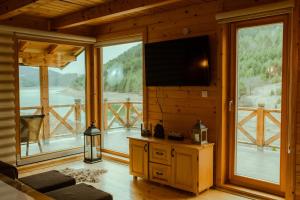 a living room with a flat screen tv and large windows at Planinska kuca ZALIV in Zaovine