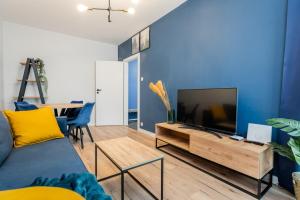 a living room with a tv and a blue wall at Nakielska Sesame Premium Apartment in Warsaw