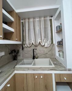 a kitchen with a white sink and a window at Sonia`s luxury apartment with jacuzzi in Kamilari