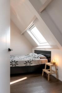 um quarto no sótão com uma cama e uma clarabóia em Zeeuws Huisje em Serooskerke