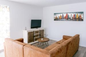 a living room with a brown couch and a tv at Zeeuws Huisje in Serooskerke