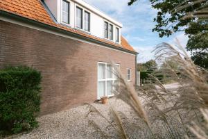 a brick house with a white window and plants at Zeeuws Huisje in Serooskerke