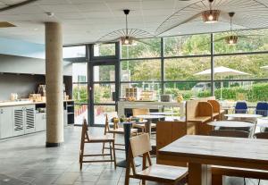 - un restaurant avec des tables, des chaises et de grandes fenêtres dans l'établissement B&B HOTEL Paris Grand Roissy CDG Aéroport, à Roissy-en-France