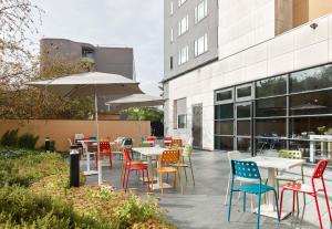 eine Terrasse mit Tischen, Stühlen und einem Sonnenschirm in der Unterkunft B&B HOTEL Paris Grand Roissy CDG Aéroport in Roissy-en-France