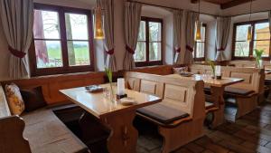 un restaurante con mesas y sillas de madera y ventanas en Hotel Landgasthof Alter Wirt, en Fischbachau