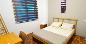 een slaapkamer met een bed, een tafel en een raam bij The Spring Homestay Apartment in Kuching