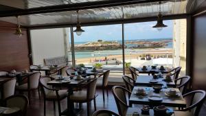- un restaurant avec des tables et des chaises et une vue sur la plage dans l'établissement Hotel De La Mer, à Trégastel