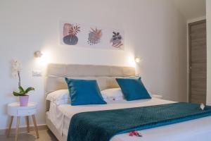 a bedroom with a large bed with blue pillows at B&B Jolie Suite in Villasimius