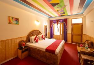 a bedroom with a bed with a colorful ceiling at Octave Hillans Manali in Manāli