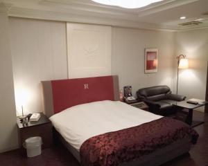Sayama的住宿－ＳＴＡＲＲＥＳＯＲＴ　Ｉ，配有一张床和一把椅子的酒店客房
