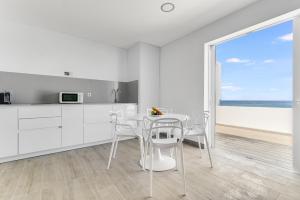 アルカスにあるHome2Book Marly Ocean View San Andrés Beachの白いキッチン(テーブル、椅子付)