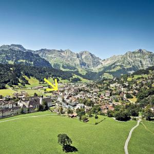 a yellow plane flying over a small town with mountains at Apartment 302 - Zentrales Studio in Engelberg