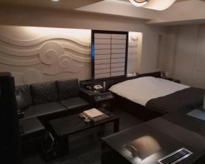 ein Hotelzimmer mit einem Bett und einem Sofa in der Unterkunft ＳＴＡＲＲＥＳＯＲＴ　Ｉ in Sayama