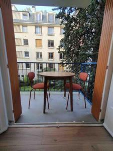 een tafel en stoelen op een balkon met een gebouw bij Château 5 min avec balcon et un Stationnement gratuit in Versailles