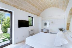 1 dormitorio con 1 cama blanca y TV en la pared en Mastropà Exclusive Palace by Raro Villas, en Massafra