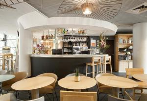 a restaurant with tables and chairs and a bar at B&B HOTEL Rueil-Malmaison Gare in Rueil-Malmaison