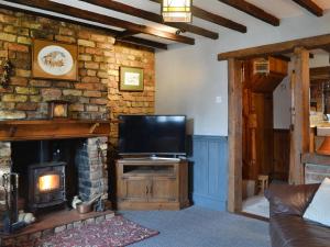 a living room with a television and a fireplace at Second Cottage in Cottingham
