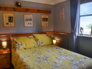 a bedroom with a bed with a yellow comforter and a window at Second Cottage in Cottingham