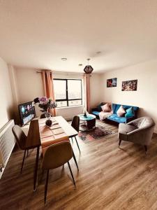 a living room with a table and chairs and a couch at BRAND NEW 5 STAR LUXURY 2 BEDROOM APARTMENT, SLEEPS 6, CENTRAL, WiFI, BIG SMART TV, ALEXA SPEAKERS, EASY ACCESS LOCK BOX ENTRY! in Liverpool