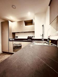 a kitchen with white cabinets and a black counter top at BRAND NEW 5 STAR LUXURY 2 BEDROOM APARTMENT, SLEEPS 6, CENTRAL, WiFI, BIG SMART TV, ALEXA SPEAKERS, EASY ACCESS LOCK BOX ENTRY! NO PARTIES! in Liverpool