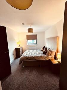 a bedroom with a bed and a desk and a window at BRAND NEW 5 STAR LUXURY 2 BEDROOM APARTMENT, SLEEPS 6, CENTRAL, WiFI, BIG SMART TV, ALEXA SPEAKERS, EASY ACCESS LOCK BOX ENTRY! in Liverpool