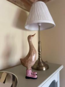 a figurine of a bird sitting on a table next to a lamp at Pond Cottage in Egerton