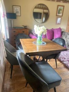 a table with chairs and a vase of flowers on it at Pond Cottage in Egerton