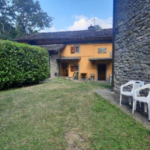 una casa con dos sillas blancas delante en La Casa della Piazzetta en Fanano